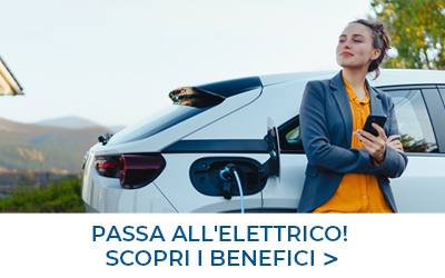 Donna appoggiata ad un'auto elettrica durante la ricarica